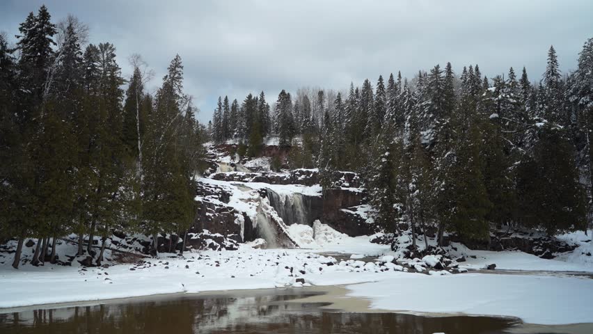Lower Falls Cascading Over Snowy Cliffs At Gooseberry Falls State Park During Winter. Lake County, Minnesota. wide static shot