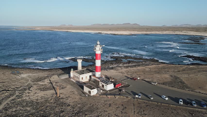 Drone footage of El Tostón Lighthouse from the side in El Cotillo, Fuerteventura, showing volcanic rocks and Atlantic shoreline.