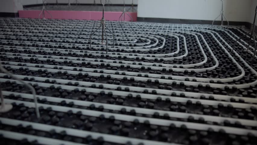 Construction workers are installing an underfloor heating system, meticulously positioning pipes