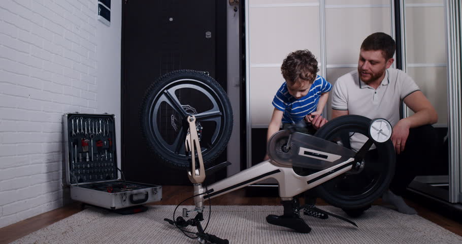 A man and boy bond while fixing a bicycle, highlighting teamwork