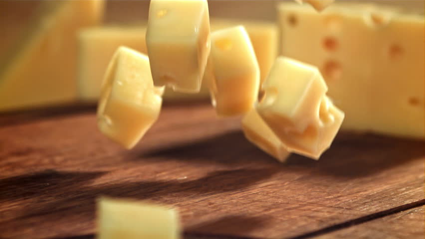 Super slow motion pieces of cheese fall onto a cutting board. Filmed on a high-speed camera at 1000 fps. High quality FullHD footage