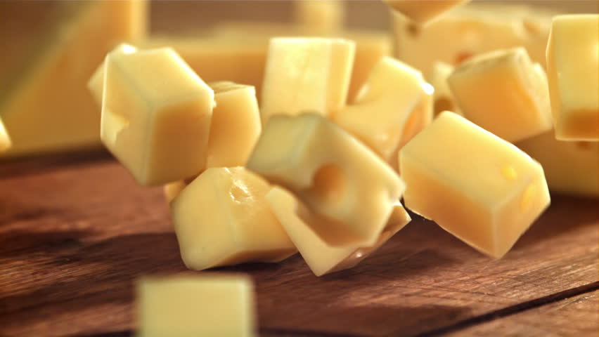Super slow motion pieces of cheese fall onto a cutting board. Filmed on a high-speed camera at 1000 fps. High quality FullHD footage