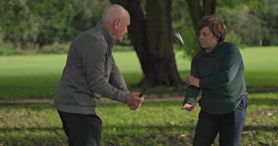 Retirement, talking and elderly friends on a golf course for help or to explain a shot technique to a player. Fitness, hobby or golfing with a senior man and woman speaking outdoor on a green