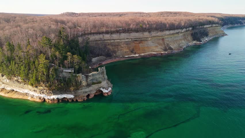 Vibrant aerial footage of North of Michigan lakeshore of dramatic sandstone cliffs and crystal-clear turquoise and emerald waters