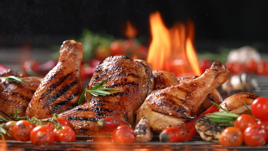 Chicken thighs grilled on hot barbecue charcoal flaming grill