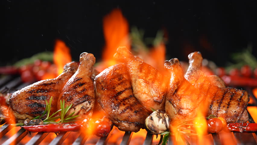 Chicken thighs grilled on hot barbecue charcoal flaming grill with spices sprinkled on top. Juicy chicken meat roasted on bbq grill.