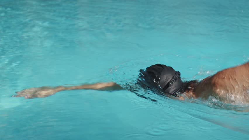 Teenager swimming in pool in freestyle style - Real time video.  Professional teen swimmer swims in an outdoor pool. Boy pro swimmer athlete conducts a training session. Healthy lifestyle  concept. 