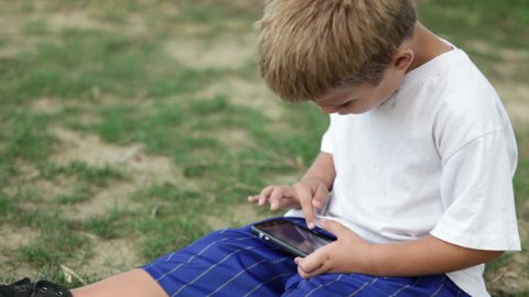 Child playing interested in cell phone outdoors