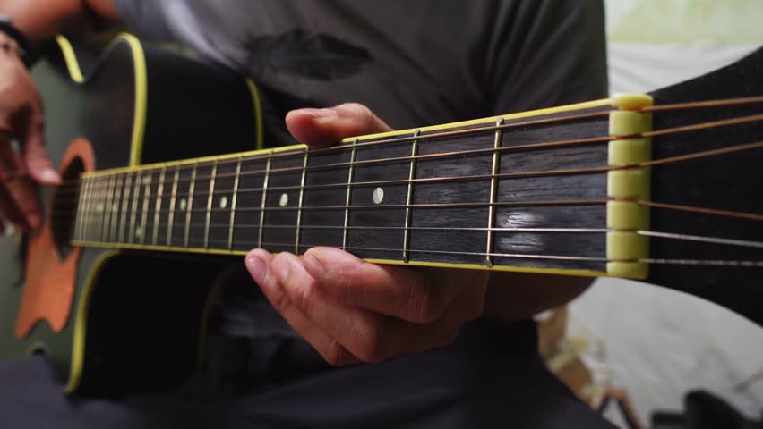 A man's hand playing the guitar chords. Close-up of a man playing acoustic guitar