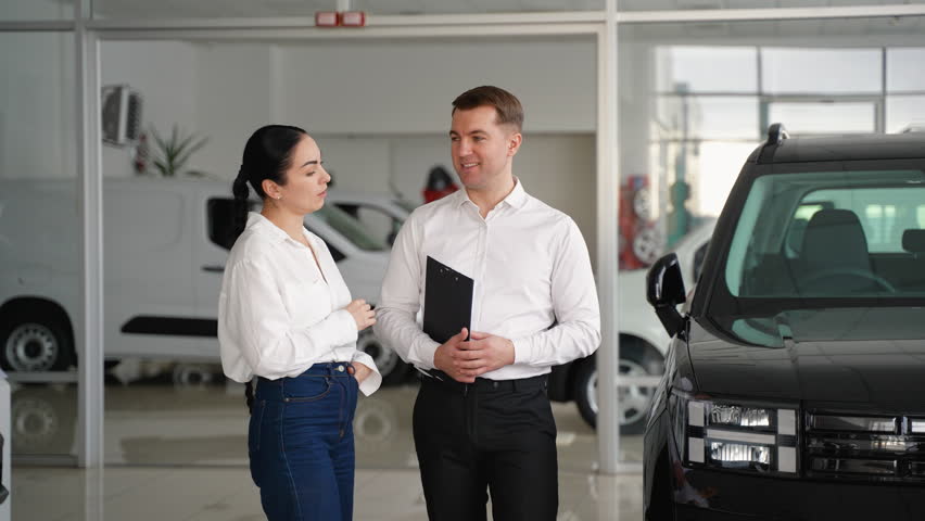 Car salesman presenting a right-hand drive car to a woman