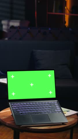 Vertical Video Black young relaxed person having green screen in his trendy loft, stylish living room decorated with cool furniture and neon lights. Casual guy relaxing on a bean bag at home