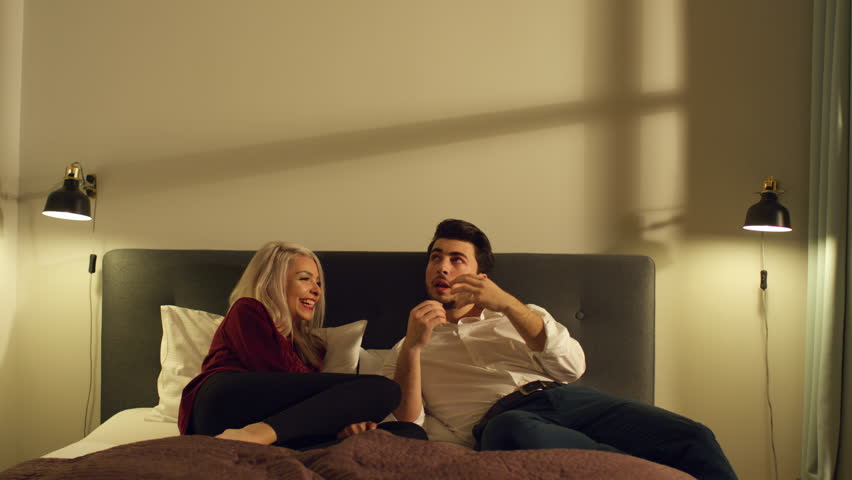 A couple enjoying a relaxed and cozy conversation on the bed.