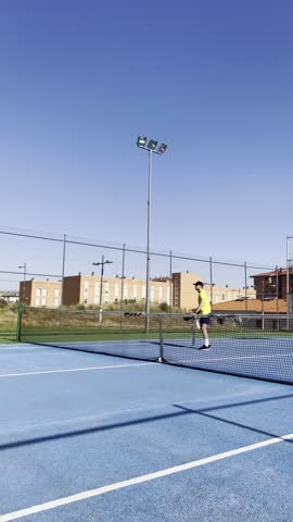 Two pickleball players practice their serves and returns on a blue court