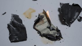 Burnt and Partially Burning Pieces of a Fifty Dollar Bill Scattered on White Table Surface with Ash and Flame Visible, Overhead View, Concept of Financial Destruction - Powered by Shutterstock - Get 15% off with code: PIKWIZARD15