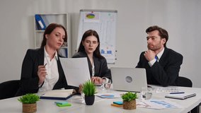 Three professionals engaged in a business meeting in an office, discussing strategy with charts on display. Slow motion - Powered by Shutterstock - Get 15% off with code: PIKWIZARD15