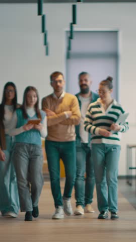 Business team in a modern open space startup office walking together. Diverse group of businesspeople smiling while having a discussion. Successful mixed race colleagues collaborating on a new project