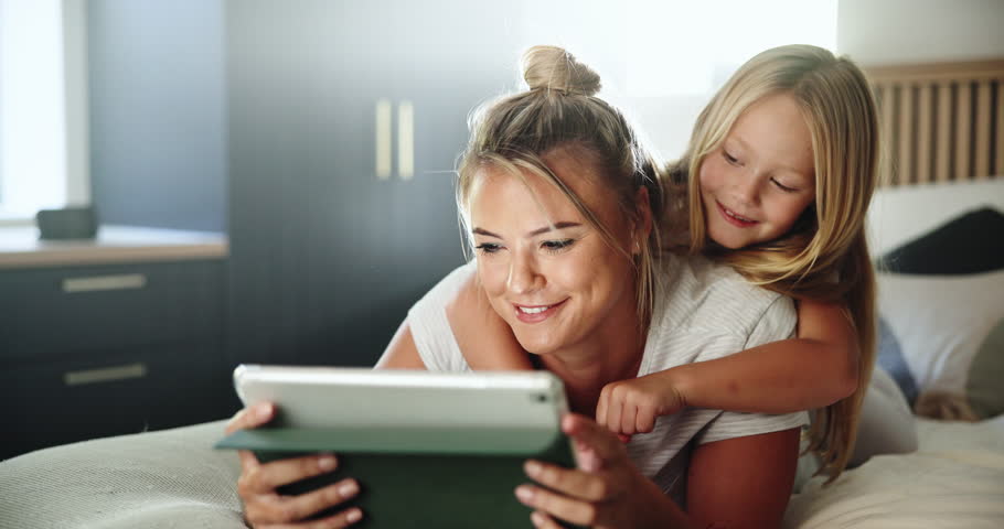 Bedroom, mother and girl with hug for tablet, streaming service and check for cartoon to watch. Home, mom and child with digital for movie website, connection and bonding together with happiness