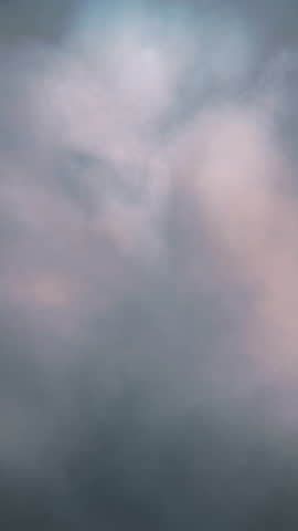 Abstract heavenly serene backdrop of soft white clouds in pastel hues with a painterly textured effect. Seamless looping animation. Vertical video.