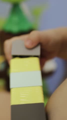  Vertical screen: A young child joyfully plays with colorful building blocks. Hands close up