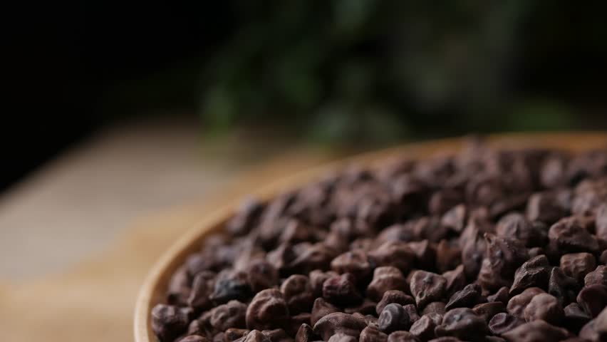 Raw Dark Brown Chickpeas (Kala Chana) on a rustic wooden table. Dry Balck chickpea (ceci neri) background close up.