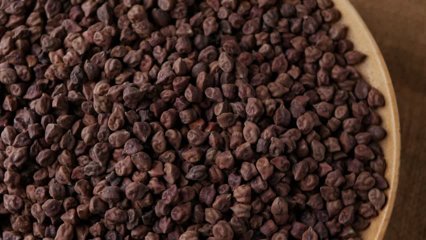 Raw Dark Brown Chickpeas (Kala Chana) on a rustic wooden table. Dry Balck chickpea (ceci neri) background close up.
