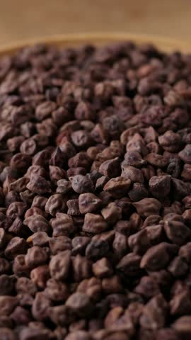 Raw Dark Brown Chickpeas (Kala Chana) on a rustic wooden table. Dry Balck chickpea (ceci neri) background close up.