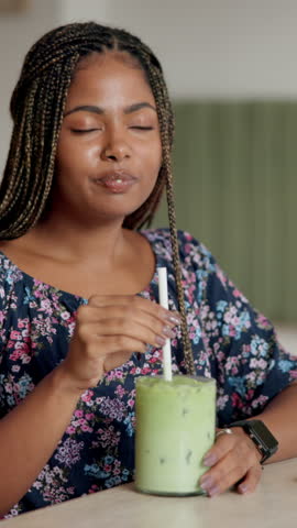 Black woman, green drink and cafe with diet for healthy beverage, matcha or nutrition at restaurant. African customer, female person and smile with organic smoothie, iced tea or shake at coffee shop