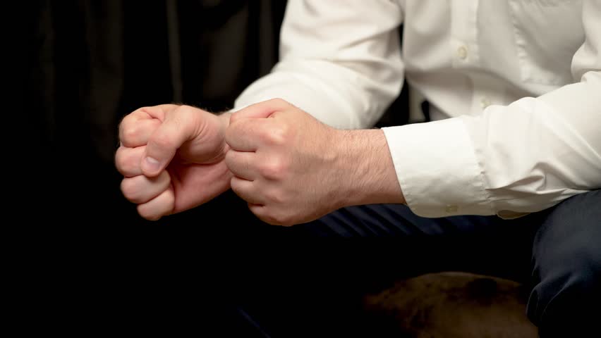 Close up Businessman clenching fists tightly, showing tension and stress. Male entrepreneur gripping fists in display of pressure and anxiety. Man squeezing hands into tight fists, illustrating stress
