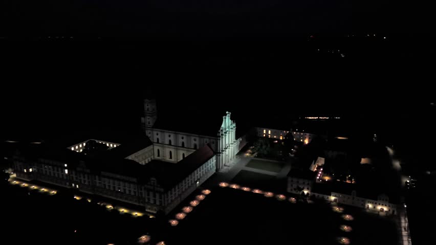 Night aerial view of Kloster Fuerstenfeld in Fuerstenfeldbruck, Bavaria, Germany. Illuminated baroque monastery complex with church St. Maria in stunning top-down panorama under twilight sky. 