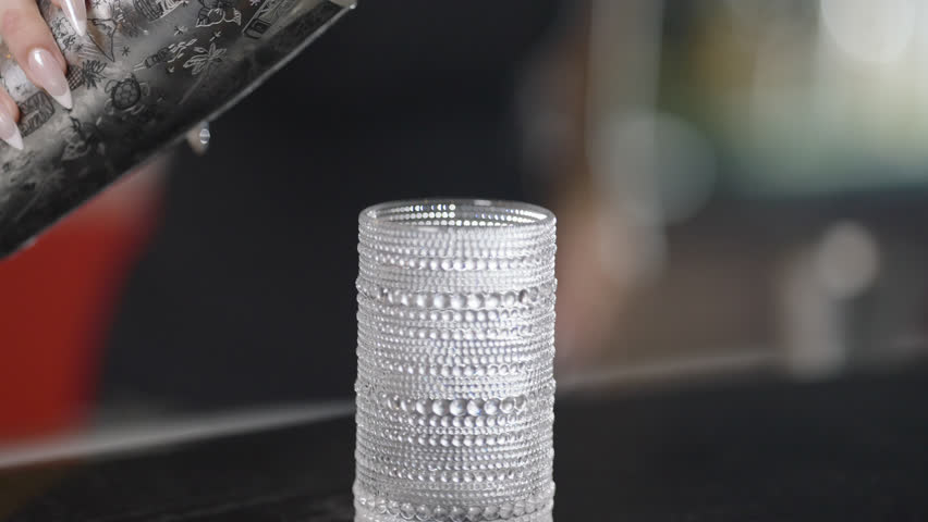 Close-up view of a sparkling glass being filled with a golden drink, highlighted by soft backlight.