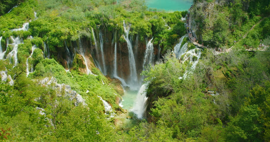 Multiple waterfalls cascade down lush cliffs into emerald pools in Plitvice Lakes