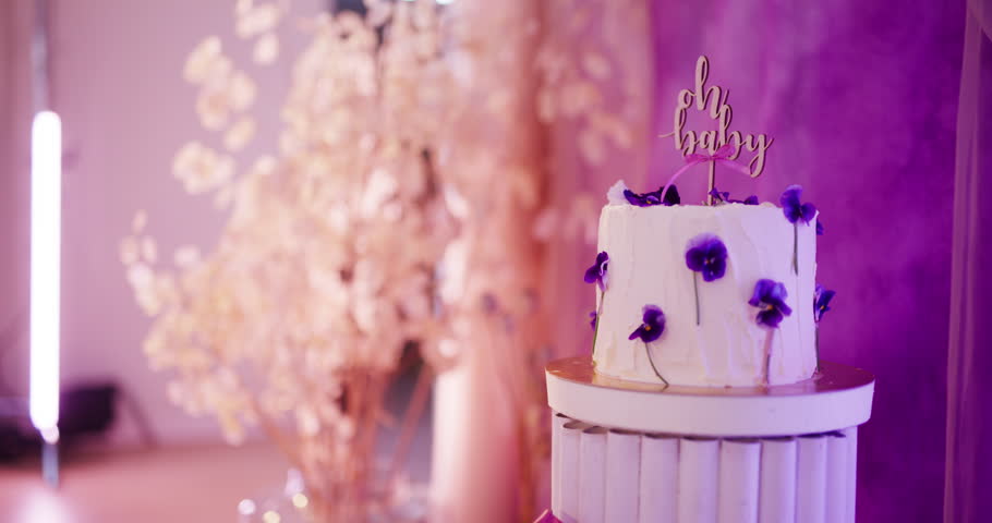Close-up of a beautiful cream cake decorated with pansy flowers for a baby shower event.