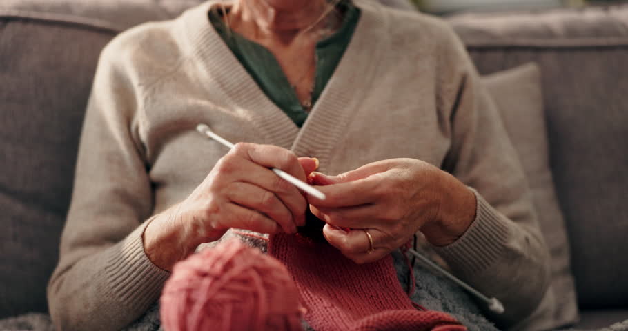 Hobby, hands and senior woman knitting in home for mental engagement, activity or creativity. Closeup, retirement and elderly female person with needles and wool for handmade clothes in living room.