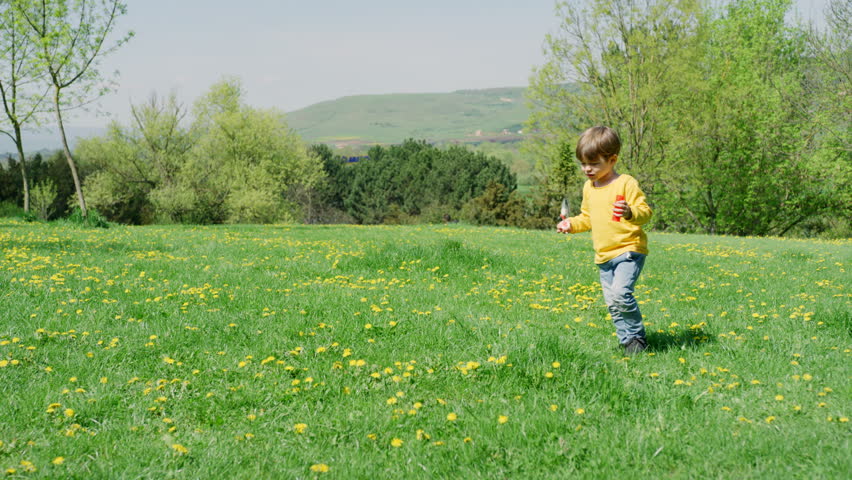 A young boy plays in a sunny field of dandelions.