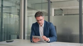 Executive man in suit working using computer for financial business banking work. Focused senior mature Indian or Latin entrepreneur businessman looking at digital tablet screen in office. Copy space  - Powered by Shutterstock - Get 15% off with code: PIKWIZARD15