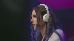 Close up profile of woman wearing white headphones looking excited and happy, face illuminated by purple neon lights, subtle smile showing joyful reaction, focused on music in studio environment - Powered by Shutterstock - Get 15% off with code: PIKWIZARD15