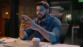 Indian Arabian businessman man guy alone in dark late night office using smartphone online chatting business employer male worker manager browsing mobile phone smiling messaging cellphone application - Powered by Shutterstock - Get 15% off with code: PIKWIZARD15