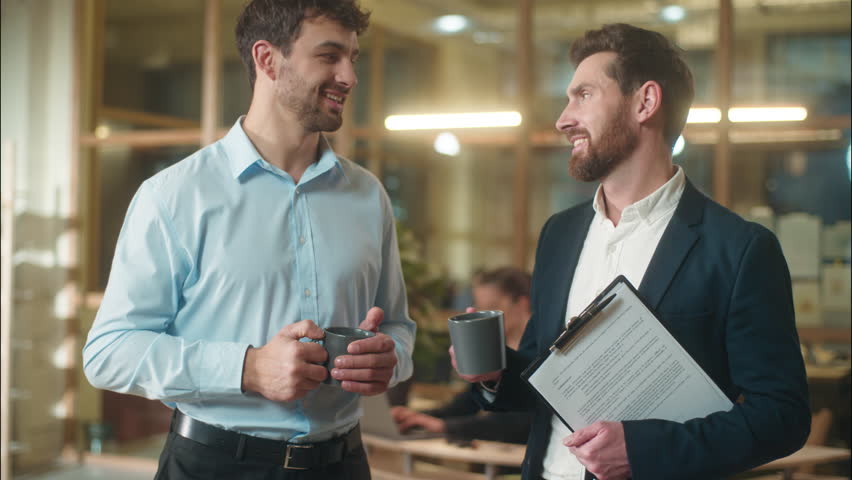Male friends colleagues co-workers business men Caucasian guys buddies drink coffee together break in office smiling businessmen partners talking discuss news in company chatting friendly conversation