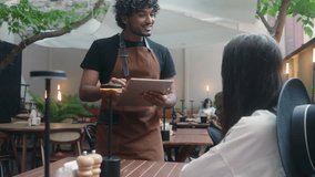 Smiling cafe worker waiter man barista chef in apron talk customer order food lunch dinner in restaurant Indian Arabian latino guy serving visitor in coffee shop client service using digital tablet - Powered by Shutterstock - Get 15% off with code: PIKWIZARD15