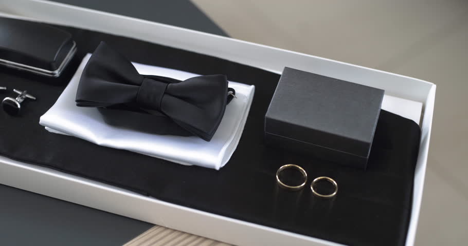 A stylish men's accessory set featuring a bow tie, cufflinks for suits, wedding rings, and two elegant boxes.