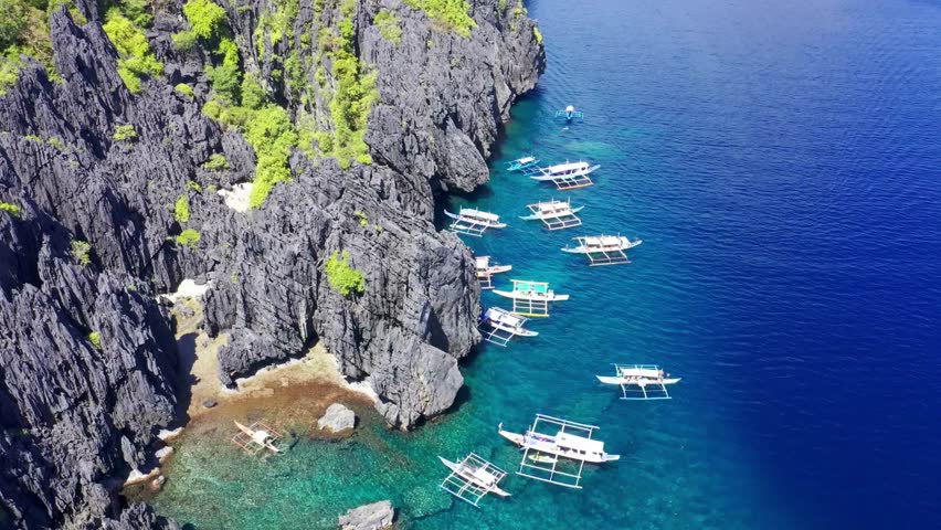Aerial View of Boats Docked Along Dramatic Limestone Cliffs and Turquoise Waters