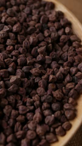 Raw Dark Brown Chickpeas (Kala Chana) on a rustic wooden table. Dry Balck chickpea (ceci neri) background close up.