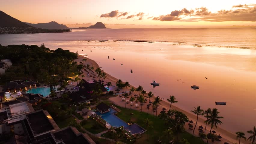 A dreamy twilight aerial of palm-lined resort nestled by the beach in beautiful Le Morne, Mauritius