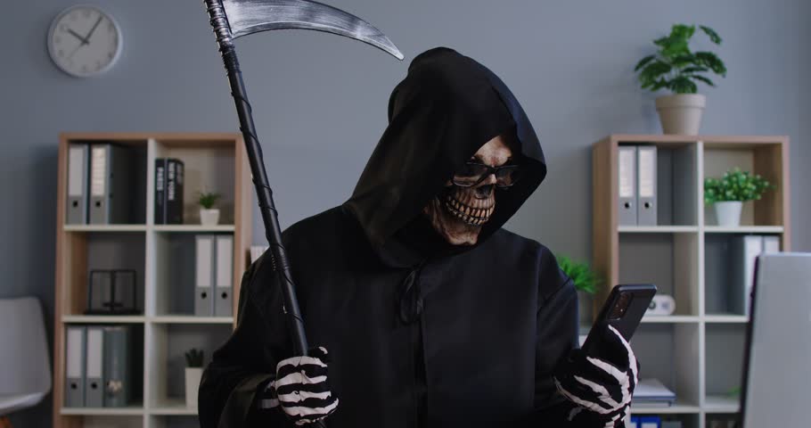 Mobile phone crime, Grim Reaper of Death finding victim online, Internet scam cybercrime fraud, illegal criminal activity, spam, Halloween costume, black hooded cape, skull face mask, skeleton gloves