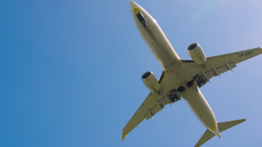 Airplane approaches landing near bright control tower under clear blue sky in a vibrant atmosphere