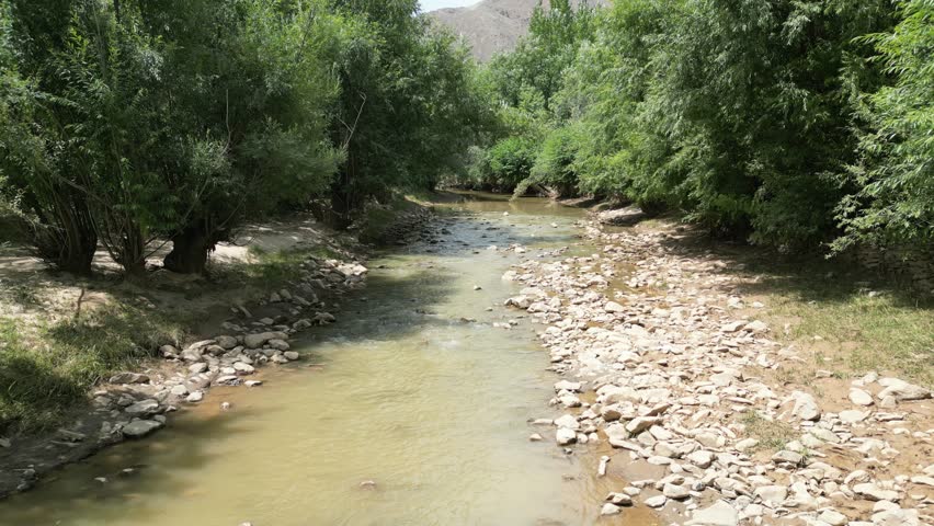 Aerial view drone footage of green river valley and rugged hills in Paktia, Afghanistan