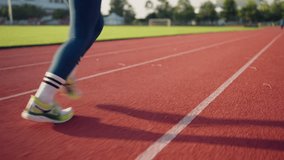 A woman running on a track. She is wearing blue pants and white socks - Powered by Shutterstock - Get 15% off with code: PIKWIZARD15