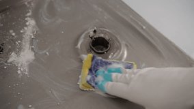 Top view of male hand scrubbing gas stove burner with sponge and cleaning agent, effectively removing grease and grime for sparkling clean kitchen and maintaining hygiene standards, slow motion. - Powered by Shutterstock - Get 15% off with code: PIKWIZARD15
