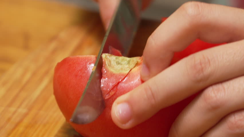 Close-Up of Hands Slicing a Tomato on a Wooden Cutting Board