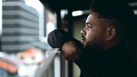 Introspective South American Young Man Gazing from Balcony - Deep Mental Reflection of 20s Black Male on Life's Challenges - Powered by Shutterstock - Get 15% off with code: PIKWIZARD15